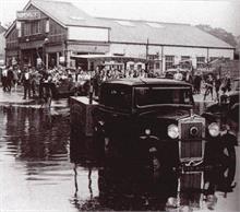 Peruzzis' ice cream cart being towed through floods under the M&GN Railway Bridge. Harmer & Scott's Garage in background