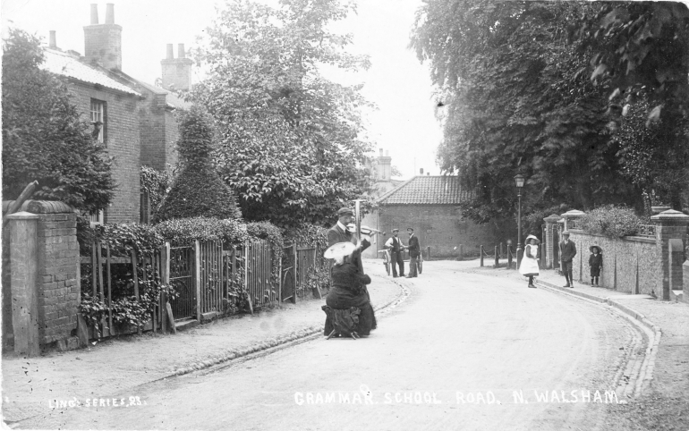 Photograph. Grammar School Road showing two buskers with violin and harp (North Walsham Archive).