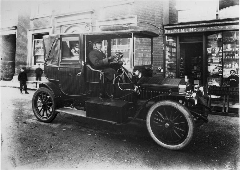 Photograph. Mrs Berney Petres' car in North Walsham Market Place 1909. The chaufeur is Mr Henry Thomas Thurling (North Walsham Archive).