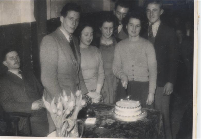 Photograph. North Walsham Youth Club, first anniversary cake cut by Edith Cutting, 1949. (North Walsham Archive).