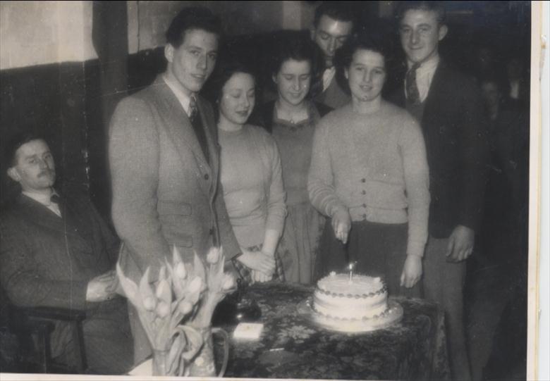 Photograph. North Walsham Youth Club, first anniversary cake cut by Edith Cutting, 1949. (North Walsham Archive).