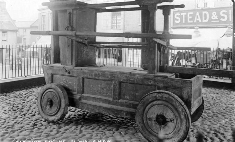 Photograph. The old Newsham Fire Engine beneath the Market Cross, North Walsham. (North Walsham Archive).