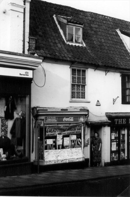 Photograph. Pam Palmer at the door of the "Yellow Shop", a confectioners at 26 Market Place, North Walsham. Opened 1965, Closed Nov. 2000. Photo:-R.M.Ling.(11) (North Walsham Archive).