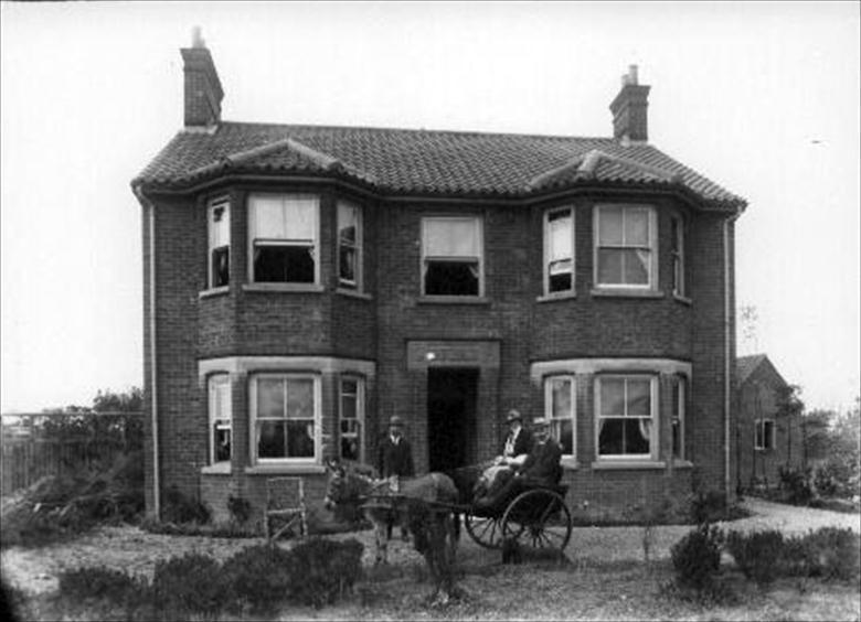 Photograph. R M Ling (1), chemist/optician, with wife, Gertrude, and brother in law in donkey trap at "Monbrecia", now Barnfield, 130 Norwich Road, Nth. Walsham. (North Walsham Archive).