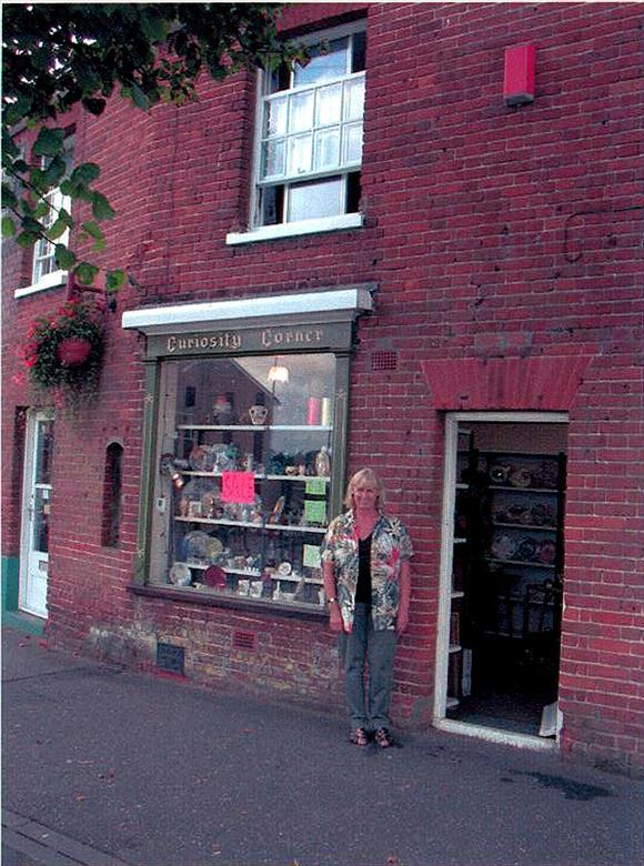 Photograph. Trish Taylor, outside her "Curiosity Corner", Vicarage Street, North Walsham (North Walsham Archive).